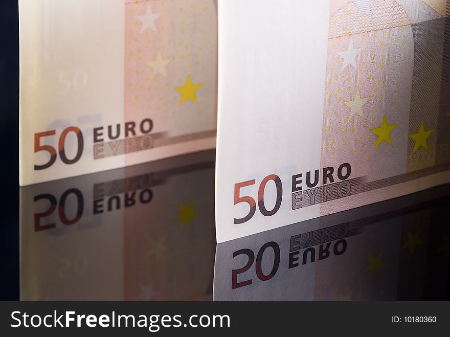 Euro banknotes isolated on black reflective background