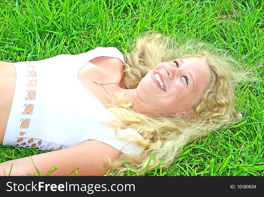 Pretty blonde girl on green grass.