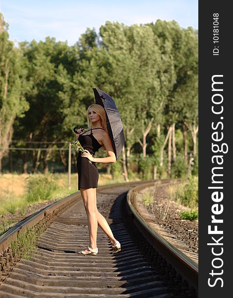 Woman in black dress with umbrella on rails