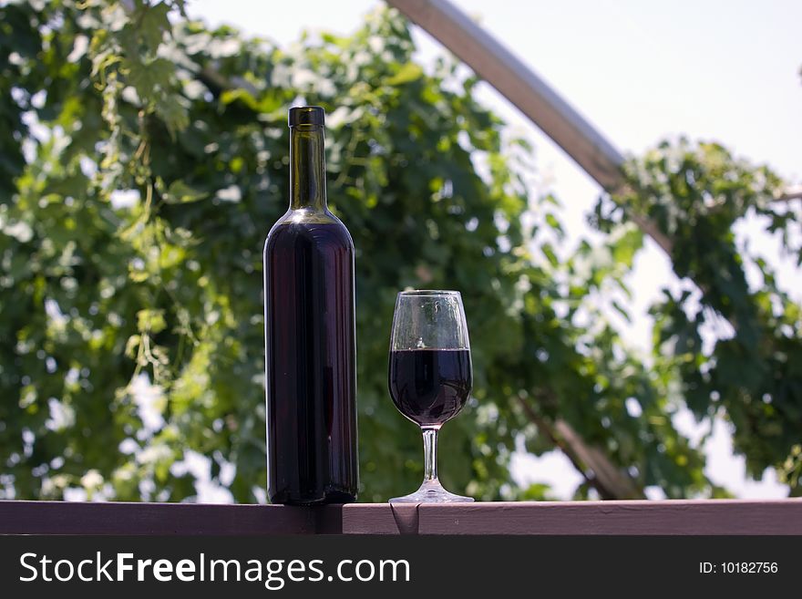 A glass and a bottle of wine on a table ready to be drunk. A glass and a bottle of wine on a table ready to be drunk