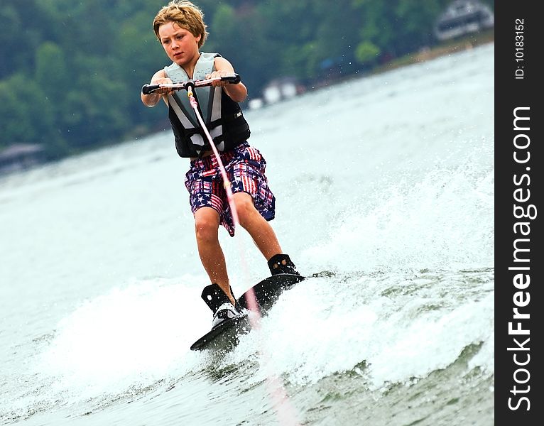 A young boy (9years old) concentrating while crossing the wake on his trick skis. A young boy (9years old) concentrating while crossing the wake on his trick skis.