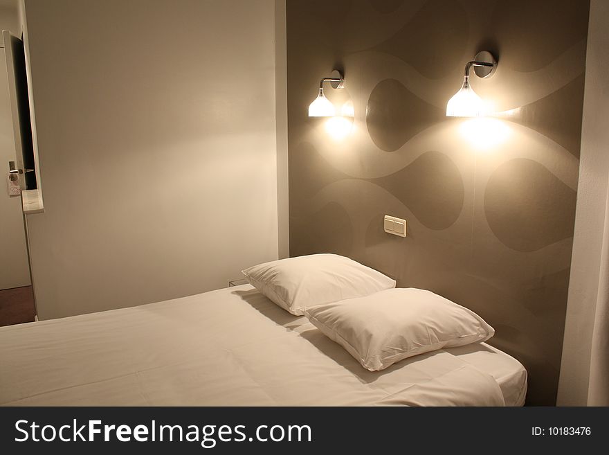 A white double bed with two lighting lamps