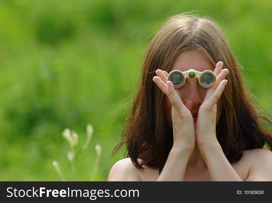 The girl on a summer meadow with opera glasses. The girl on a summer meadow with opera glasses