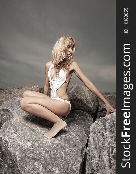 Young woman posing on rocks by the beach. Young woman posing on rocks by the beach