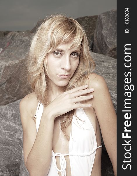 Young woman posing on rocks by the beach. Young woman posing on rocks by the beach