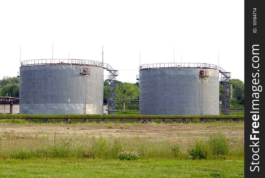 Two huge industrial capacities standing against a green grass