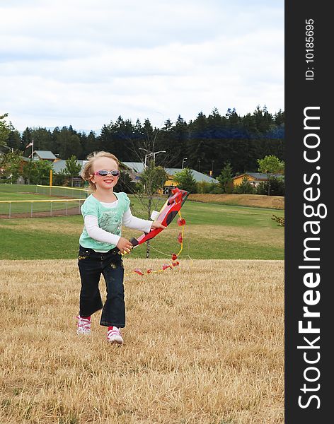 Smiling kid playing with kite in the park.