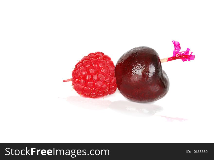 Black fresh ripe cherry with ruspberry on the wood pick isolated on the hate background. Black fresh ripe cherry with ruspberry on the wood pick isolated on the hate background.