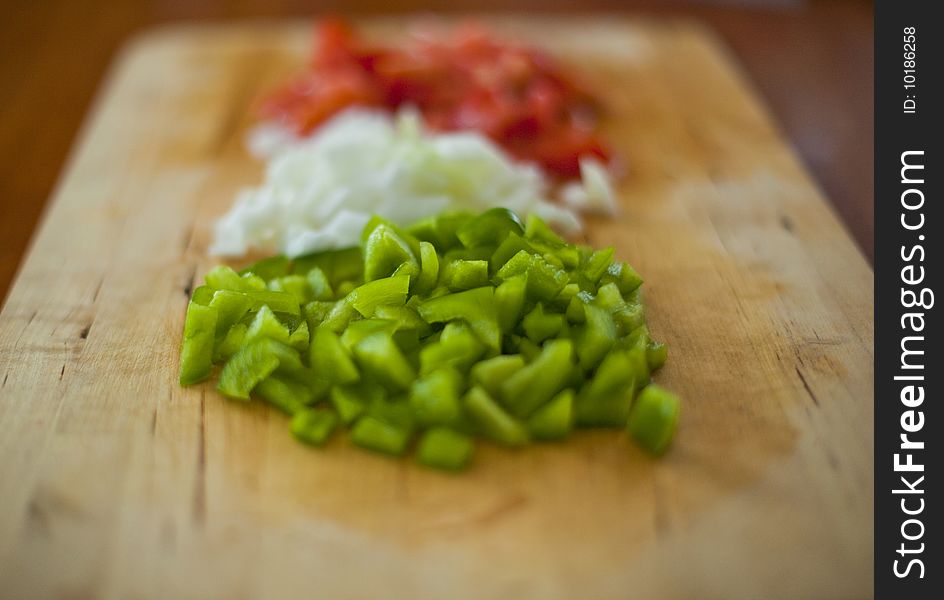 Chopped green and red peppers and some white onions on a wooden chopping board. Chopped green and red peppers and some white onions on a wooden chopping board.