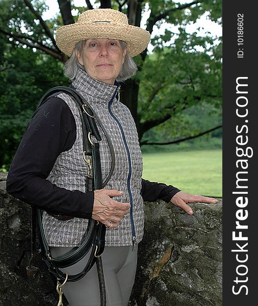 Color photograph of a senior equestrian getting ready to saddle up her horse for a ride. Color photograph of a senior equestrian getting ready to saddle up her horse for a ride.