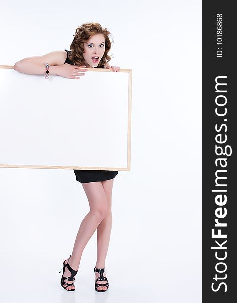 Young emotional woman on isolated background holding a blank board