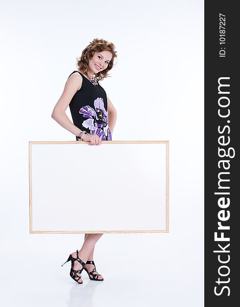 Young emotional woman on isolated background holding a blank board