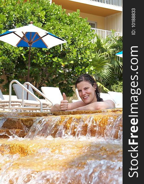 Young woman in a beautiful pool with palms in the background. She is showing a thumbs up sign. Young woman in a beautiful pool with palms in the background. She is showing a thumbs up sign.