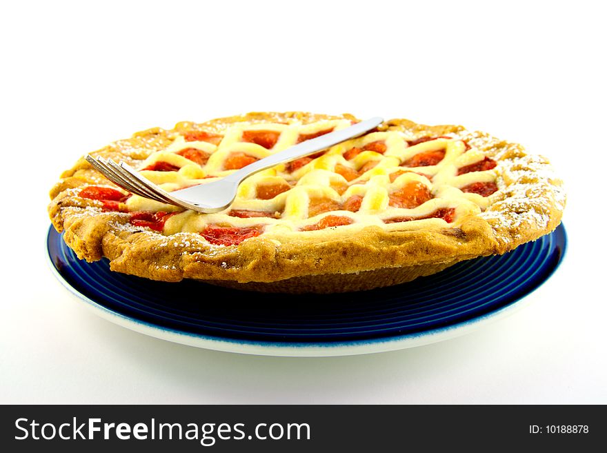 Whole apple and strawberry pie on a blue plate with a small fork on a white background. Whole apple and strawberry pie on a blue plate with a small fork on a white background