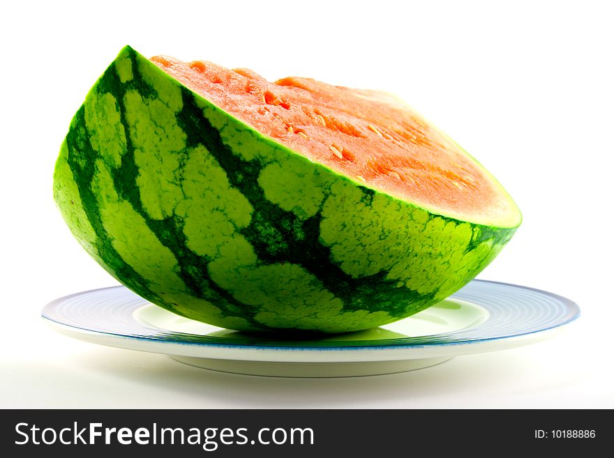 Slice of watermelon with green skin and red melon with seeds on a blue plate with a white background