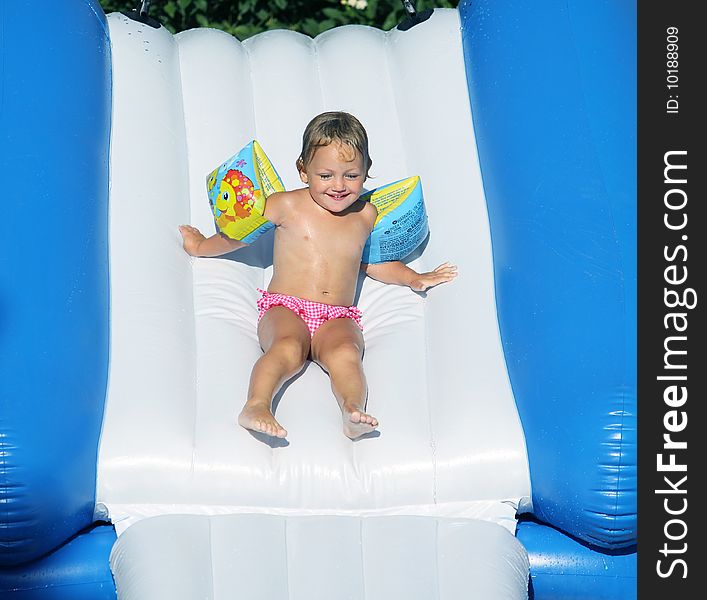 A young pretty girl going down a water slide wearing armbands as protection. A young pretty girl going down a water slide wearing armbands as protection