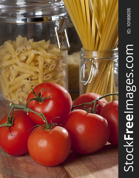 Fresh tomatoes in front of a container with raw spaghetti