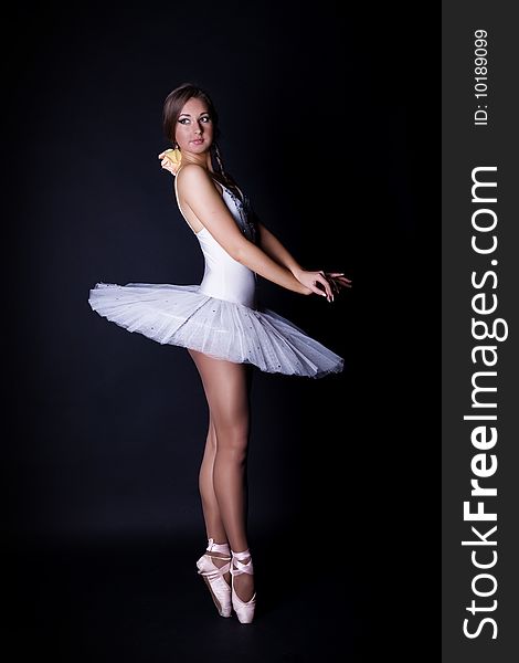 Ballerina in white tutu on black background