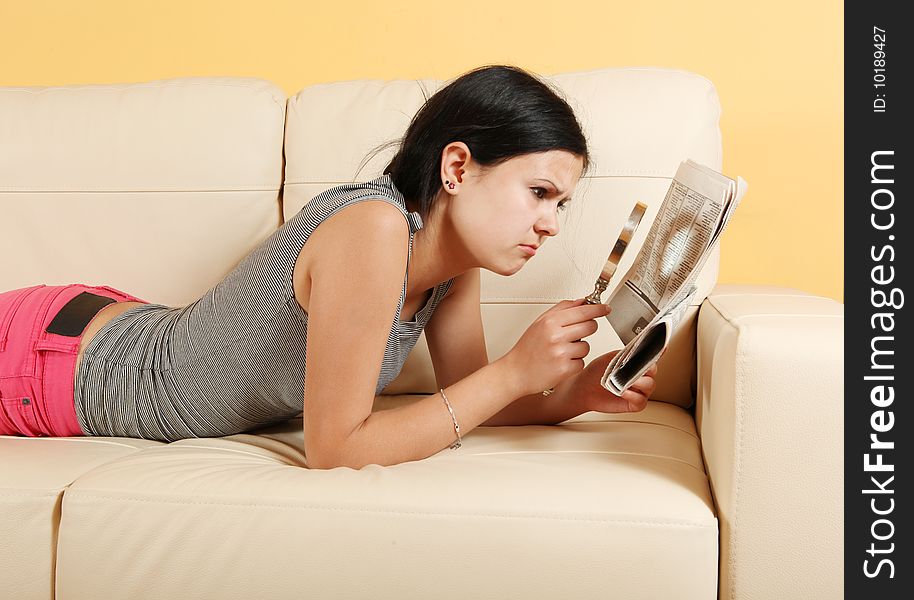 Girl reading a newspaper on white sofa