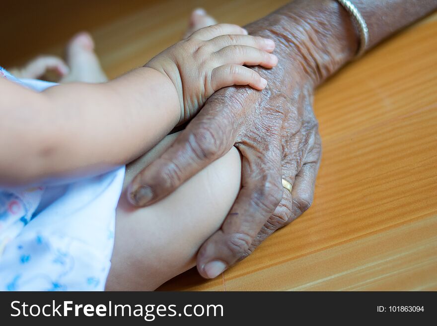 Hand baby on hand elderly lady.