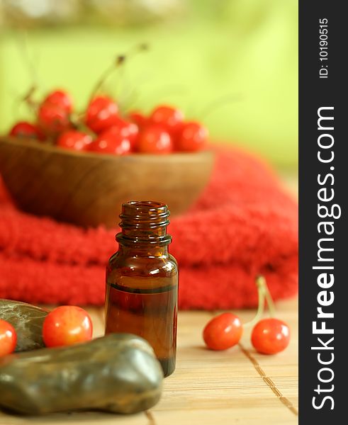 bottle of essence oil, fresh cherry and red towel
