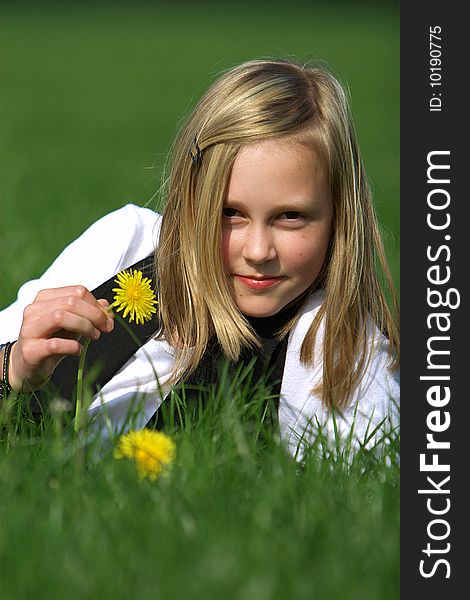 Blonde girl smiling and lies in the grass with a flower. Blonde girl smiling and lies in the grass with a flower