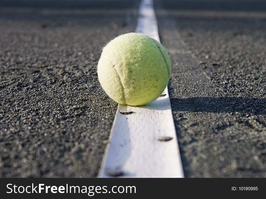 Closeup of a tennisball on the line of a clay court