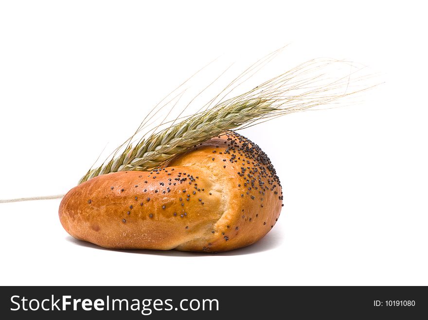 Single fresh bun and ear of wheat, soft shadow on white