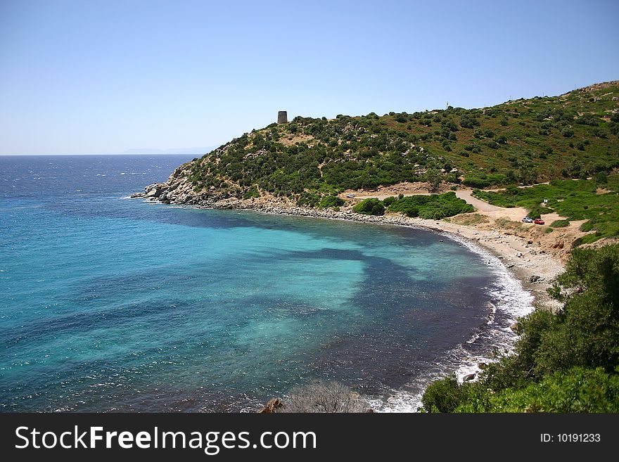 Beach of Cala Reggina and historical saracen tower above, Sardinia - Italy