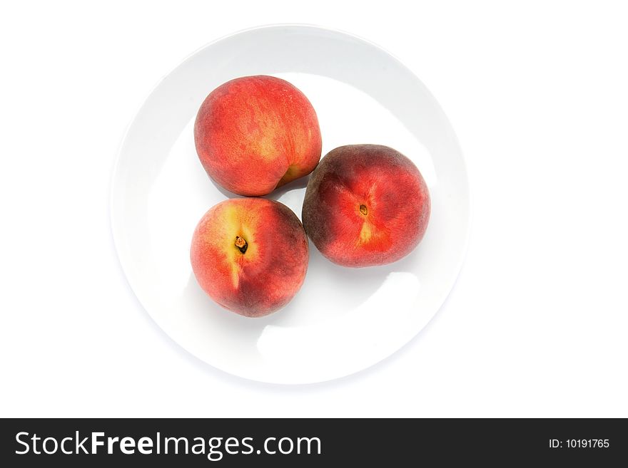Three fresh peaches on white ceramic plate. Three fresh peaches on white ceramic plate