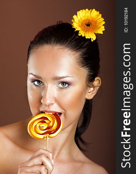 Beauty portrait of a young woman with a lollipop and a flower. Beauty portrait of a young woman with a lollipop and a flower