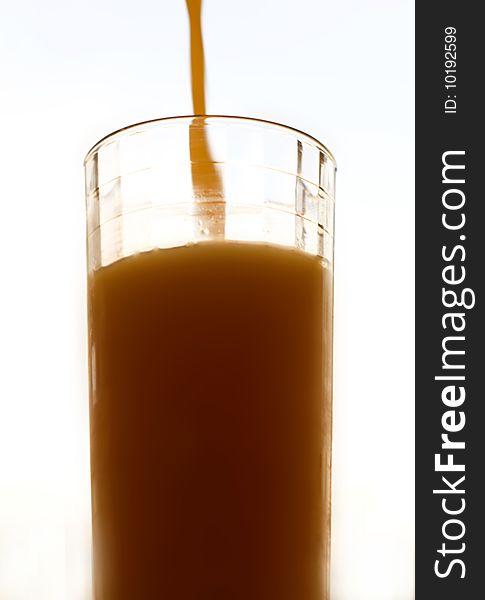 A closeup of a large glass of fresh orange juice as it is being filled. A closeup of a large glass of fresh orange juice as it is being filled.