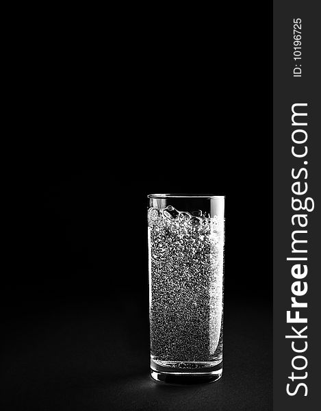 Glass of mineral water is isolated against a black background