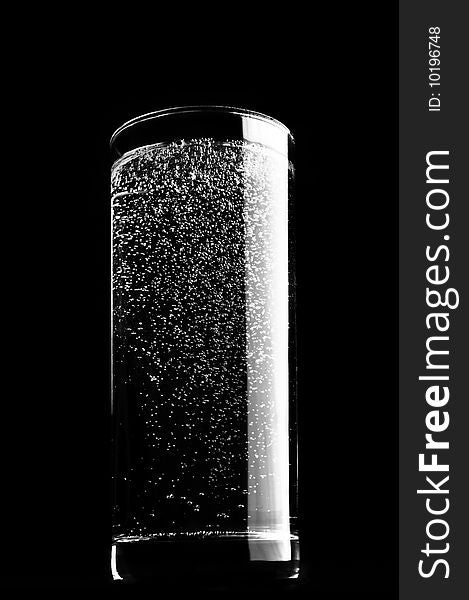 Glass of sparkling water is isolated against a black background