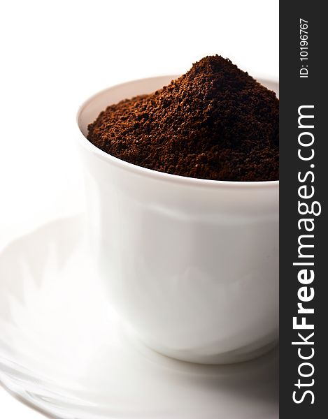 Pile of fresh ground coffee in a cup is isolated against a white background. Pile of fresh ground coffee in a cup is isolated against a white background