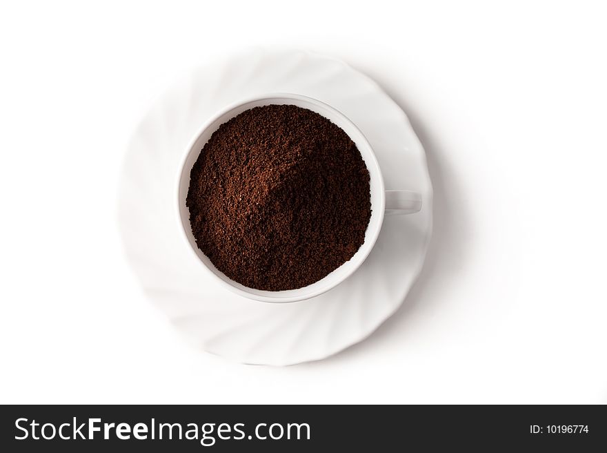 Pile of ground coffee in a cup is isolated against a white background