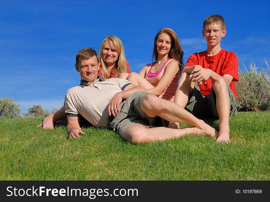 Family of four sit on grass
