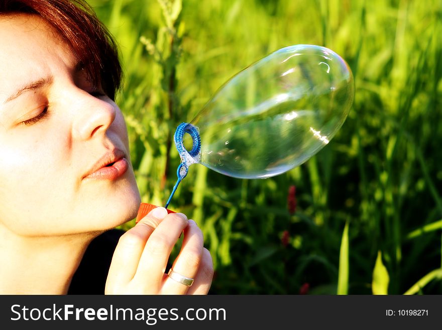 A woman is blowing a soap bubble