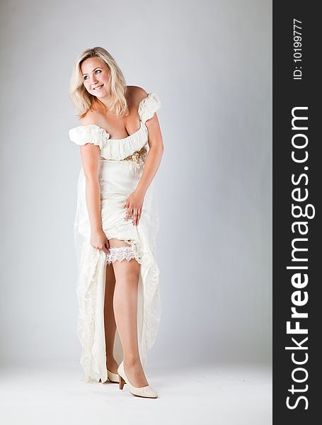 Young bride in white dress on gray background