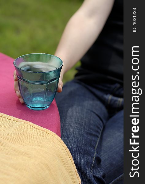 Female hand holding a turquoise glass on purple tablecloth
