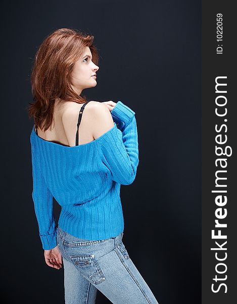 girl,in blue jeans and blue blouse posing, on black background. girl,in blue jeans and blue blouse posing, on black background