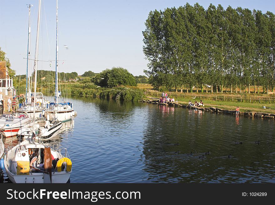 Summer river scene with boats and people relaxing. Summer river scene with boats and people relaxing