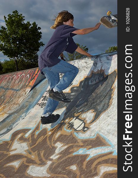 A young boy skateboarding up a ramp at a skate park. A young boy skateboarding up a ramp at a skate park