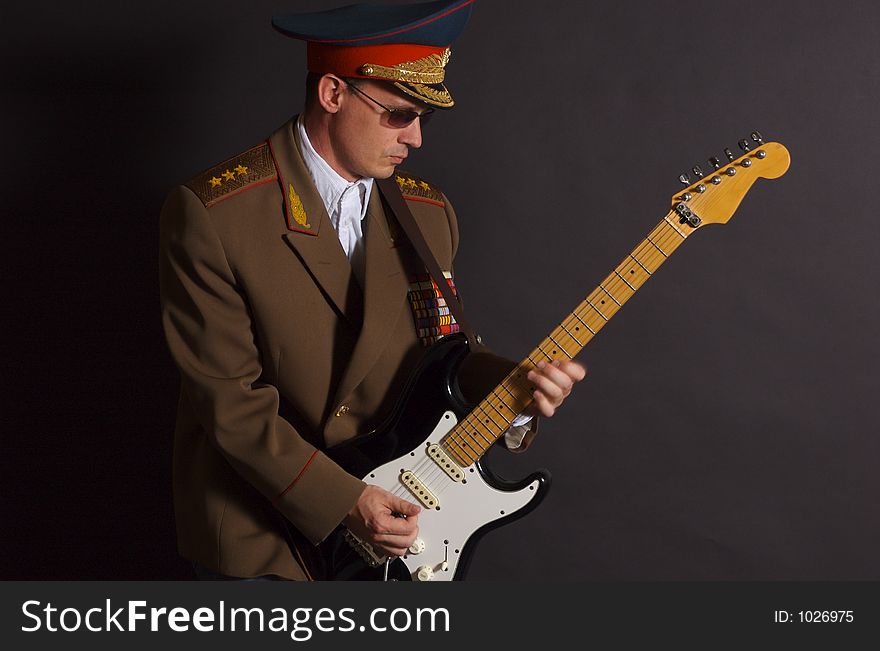 Portrait of a man dressed in a military uniform, playing an electric guitar. Portrait of a man dressed in a military uniform, playing an electric guitar