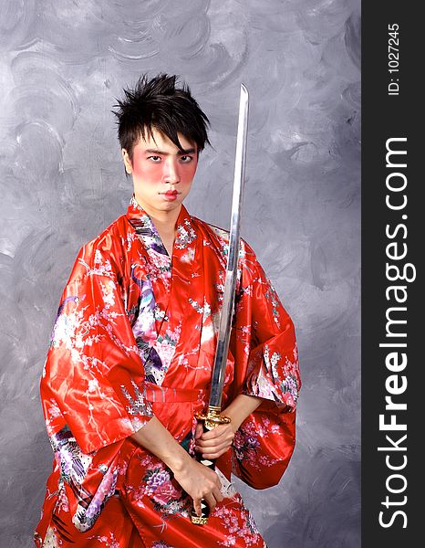 A man in a Geisha outfit, holding a sword. A man in a Geisha outfit, holding a sword