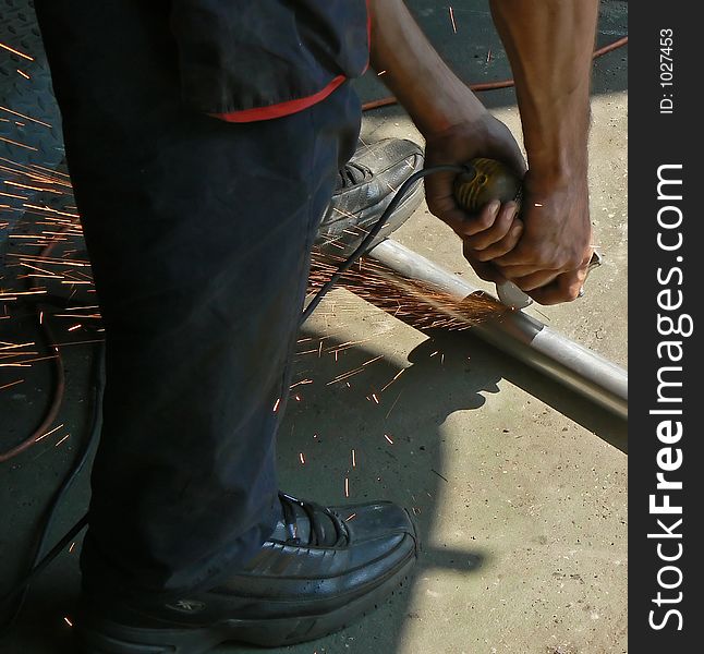 A worker grinding and cutting a pipe. A worker grinding and cutting a pipe