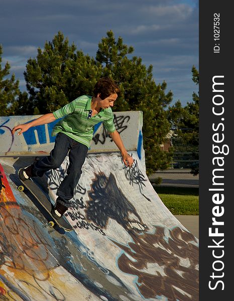 A young boy skateboarding up a ramp at a skate park. A young boy skateboarding up a ramp at a skate park