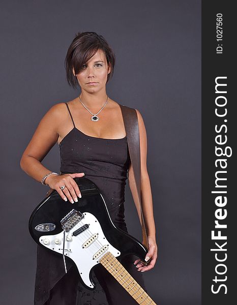 A woman in a black dress holding an electric guitar. A woman in a black dress holding an electric guitar