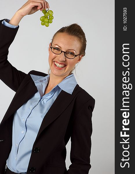 A woman holding grapes over her head, and laughing