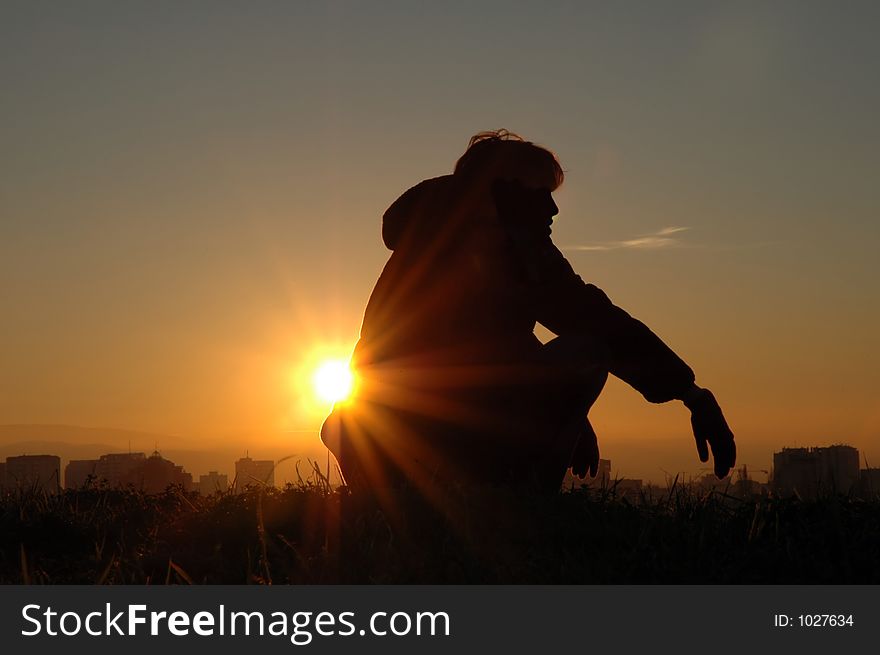 Girl sitting on the hill, watching the nightfall over the city. Girl sitting on the hill, watching the nightfall over the city